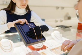 woman-choosing-golden-chain-in-jewelry-store-4TE96XP
